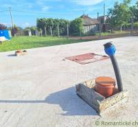 Concrete surface with a pipe and the surrounding garden and rural architecture.