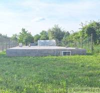 Concrete foundation in the garden, surrounded by lawn and fence. Ideal for building a small house.