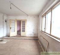 Interior of a cabin for renovation with large windows, white walls, and double doors.