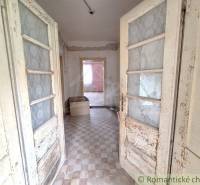 A cottage with vintage doors, tiled floor, a room with a box, plaster peeled off.