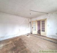 White room with double doors, worn floor, view of entrance to another room, cottage.