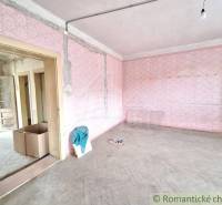 A room with pink walls, wooden floors in a cottage ready for renovation.