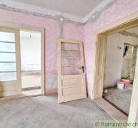 An interior with pink wallpaper and old doors, suggesting the state of cottage renovation.