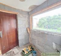 An interior with an unplastered wall, door, window, and tools, suitable for a cottage and gardeners.