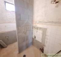 Bathroom under renovation with tiles in a cottage. Original plumbing and sink.