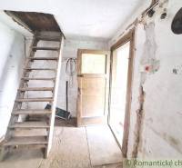 A wooden ladder leads to the attic, next to it are old doors in the cabin.