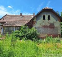 An old family house with a damaged facade in a natural environment.