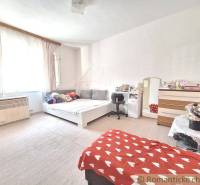 A room in a family house with a bed, a work desk, and pleasant natural lighting.