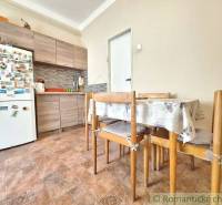 A kitchen with a family house, contains wooden furniture and a refrigerator with magnets.