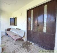 Entrance area of a unique property with a bench and large wooden doors.