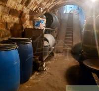 Old wine cellar with barrels and brick walls, part of unique properties.