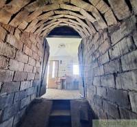 Arched passage in the Peculiar Properties leading to a room with a wooden table and chairs.