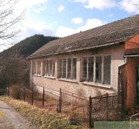 A family house surrounded by nature, fenced on a country road.