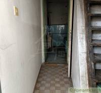 Entrance hallway with wooden stairs and tiled walls in a neglected family house.