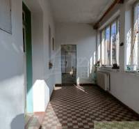 A sunlit porch in a family house with large windows and a tiled floor.