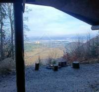 A view from the shelter to a picturesque winter landscape with a family house in the valley.