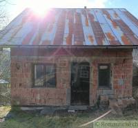 In the picture is an old brick cottage with sunlight shining through the rusty roof.
