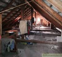 Attic in a rural family house with wooden beams and clutter.