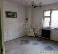 An empty room with white tiles, a radiator, and a painting in an older family house.