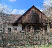 A country house surrounded by trees and a fence, with a blue sky overhead.