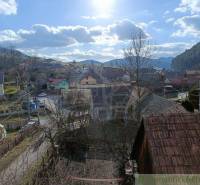 A village surrounded by hills, family houses with a rural atmosphere, and a blue sky.