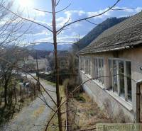 An old building on a sunny slope in a mountain village with a family house.