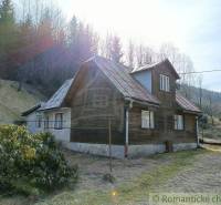 A rustic cottage in a mountainous landscape surrounded by forests, ideal for relaxation in nature.