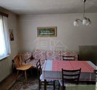 A room with wooden chairs, a table, and a red tablecloth, ideal for a cottage.