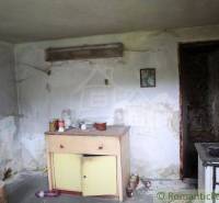 In the room of the family house, there is old furniture and kitchen appliances in need of repair.