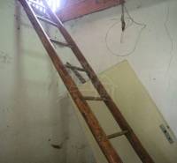 A wooden ladder leads to the attic through an opening in the wall of the family house.