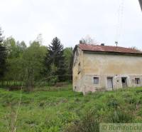 An old family house in the middle of greenery, surrounded by trees and lush nature.