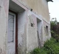 An abandoned family house with cracked walls and an overgrown yard.