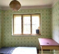 Green wallpaper, a table, and simple lighting characterize the room in the family house.
