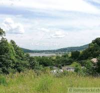 Gardens and natural landscape, overlooking a small village surrounded by mountains and a river.