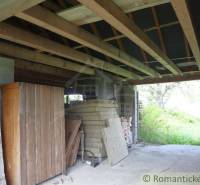 A construction shelter, wooden structure, cabinets, and nature behind the family house.