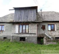 An older rural family house with stone walls and a shingle roof.
