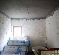 A room in a family house with white walls, bundles of insulation material, and a small window.