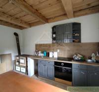 Wooden ceiling in the kitchen with a traditional fireplace and kitchen unit in a family house.