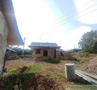 A family house in the countryside, surrounded by building materials and nature.