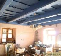An old interior with a blue wooden ceiling, windows, a swing, and furniture in a family house.
