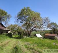 A visible family house in the countryside with a garden, surrounded by trees and a blue sky.
