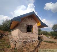 A small family house under construction in a natural environment with unfinished walls.