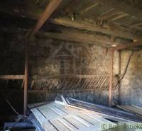 Description of a room in an older family house with stone walls and a wooden ceiling.