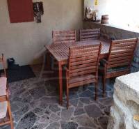 An outdoor terrace with wooden furniture surrounded by stones, ideal for family gatherings.