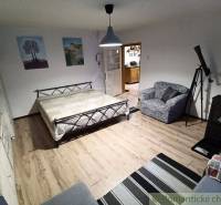 Interior of a family house with a bed, chair, fireplace, and wooden floor.