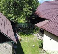 A courtyard with a family house, garden, and a beautiful view of trees and greenery.
