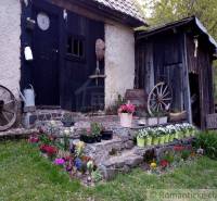 A historical cottage with garden flowers and wooden barrels in picturesque nature.