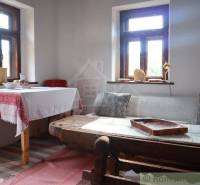The interior of the cottage with a wooden table, traditional tablecloth, and comfortable seating by the window.