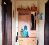 A cottage with an entrance hallway and a cabinet, woven baskets, and a rug on the floor.