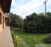 A cottage surrounded by greenery, a wooden fence, and a garden. A peaceful environment.